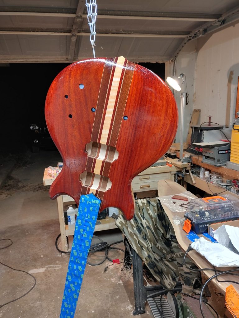 Finished padauk guitar body hanging in the shop